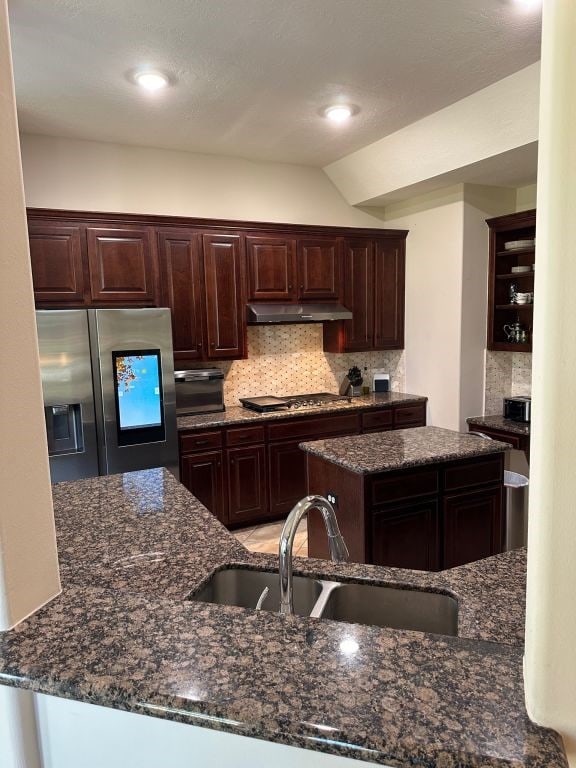 kitchen featuring dark stone countertops, stainless steel appliances, dark brown cabinetry, and sink