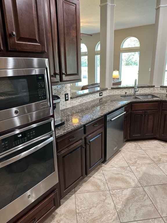 kitchen featuring dark brown cabinetry, stainless steel appliances, sink, and stone countertops