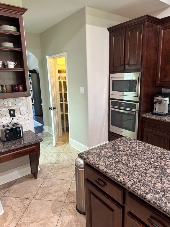 kitchen featuring dark stone countertops, dark brown cabinetry, and stainless steel appliances