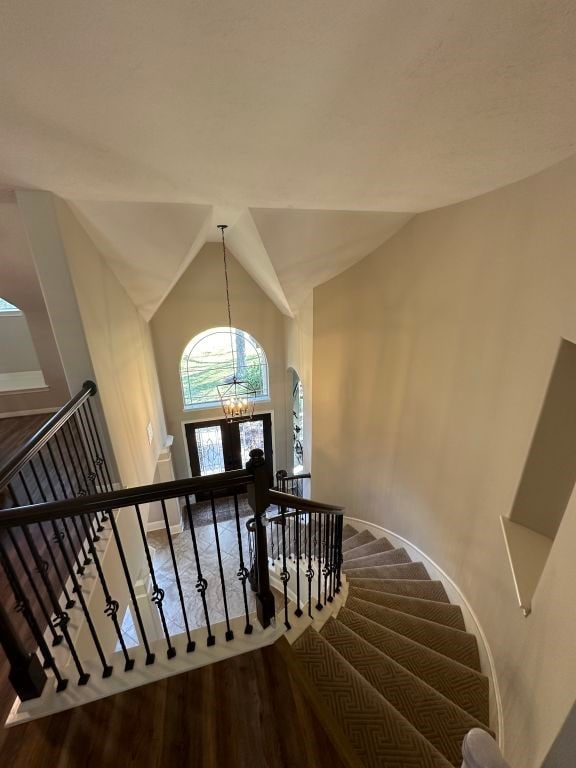 staircase with lofted ceiling, a chandelier, and hardwood / wood-style flooring