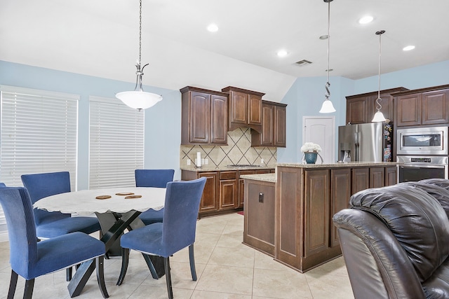 kitchen with a kitchen island, dark brown cabinets, hanging light fixtures, stainless steel appliances, and vaulted ceiling