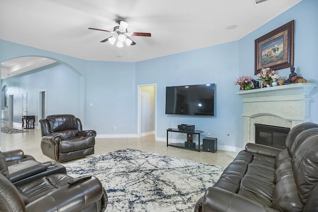 tiled living room with a premium fireplace and ceiling fan