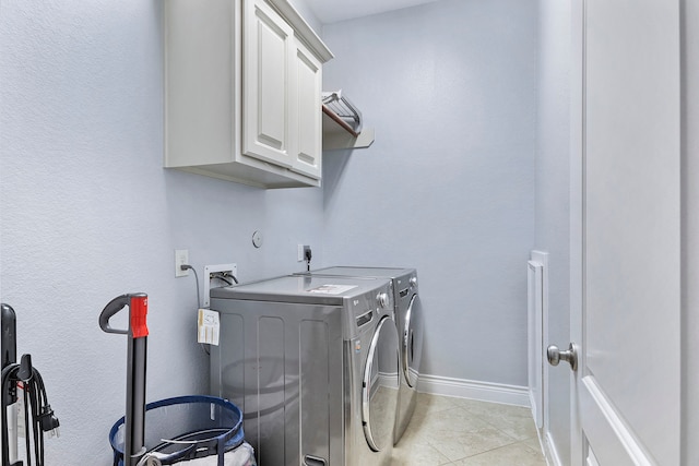 laundry area featuring light tile patterned floors, cabinets, and washer and clothes dryer