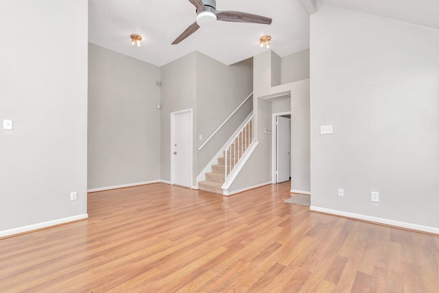 unfurnished living room featuring light hardwood / wood-style floors, ceiling fan, and a towering ceiling