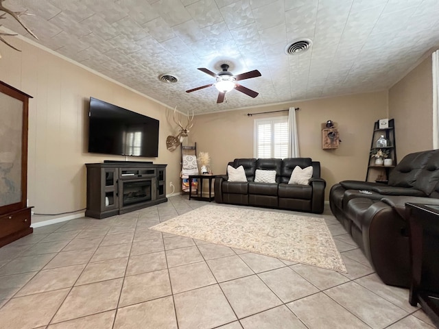 living room featuring ceiling fan, light tile patterned floors, a textured ceiling, and ornamental molding