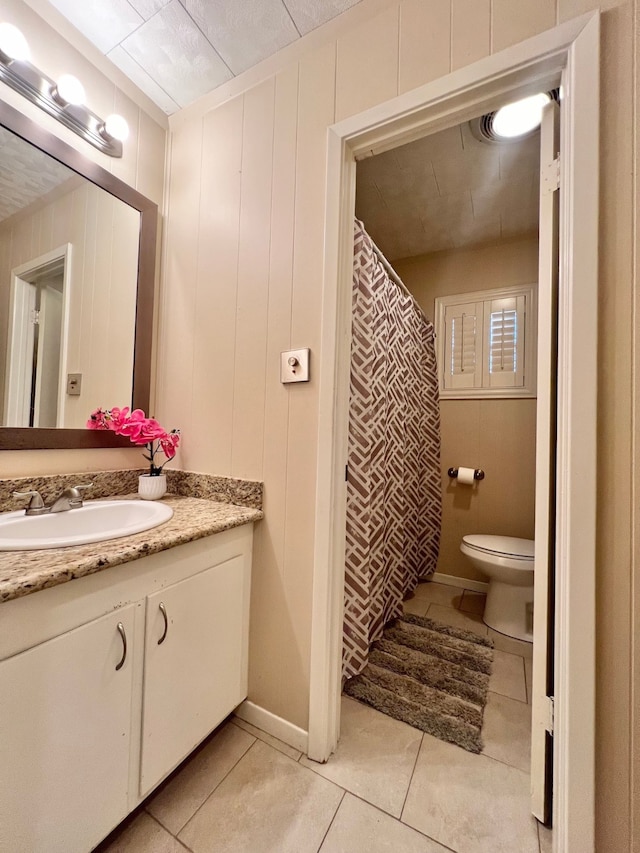 bathroom featuring wood walls, tile patterned flooring, vanity, and toilet