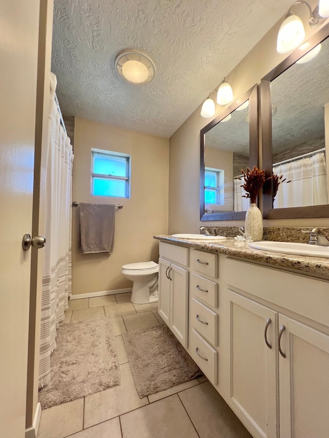 bathroom with tile patterned floors, vanity, a textured ceiling, and toilet