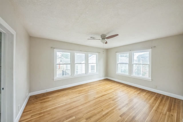 spare room with ceiling fan, a textured ceiling, light wood-type flooring, and plenty of natural light