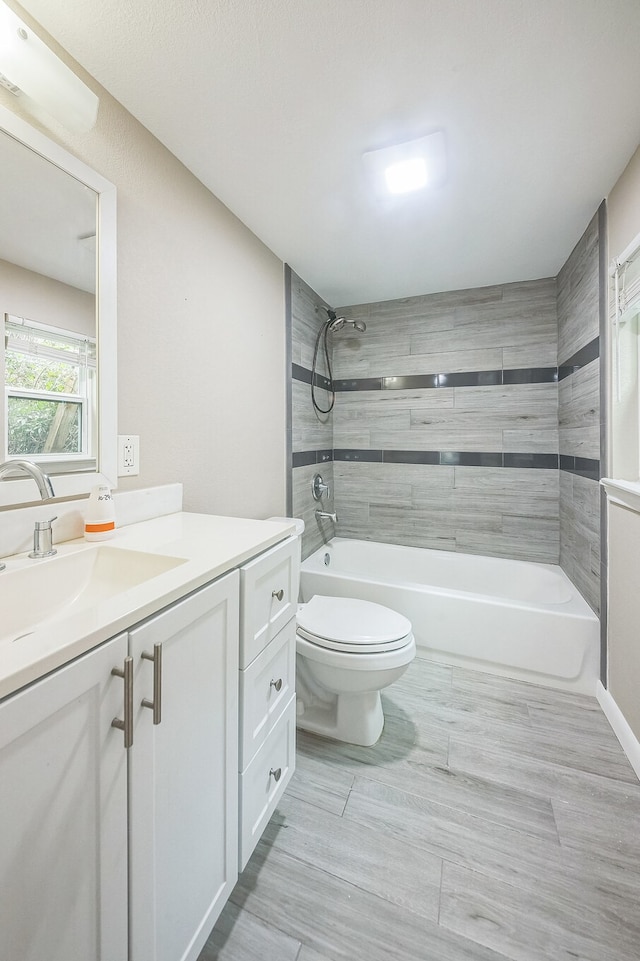 full bathroom featuring vanity, tiled shower / bath combo, hardwood / wood-style flooring, and toilet