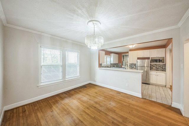 2409 Arbor St, Houston, TX 77004 - kitchen featuring appliances with stainless steel finishes, tasteful backsplash, light wood-type flooring, a chandelier, and white cabinetry