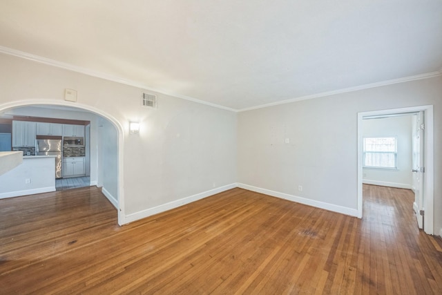 2409 Arbor St, Houston, TX 77004 - unfurnished living room featuring arched walkways, crown molding, baseboards, and wood-type flooring