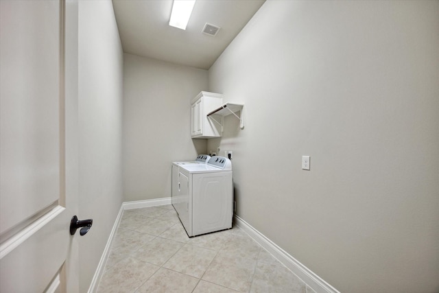 laundry area featuring washer and dryer, light tile patterned flooring, and cabinets