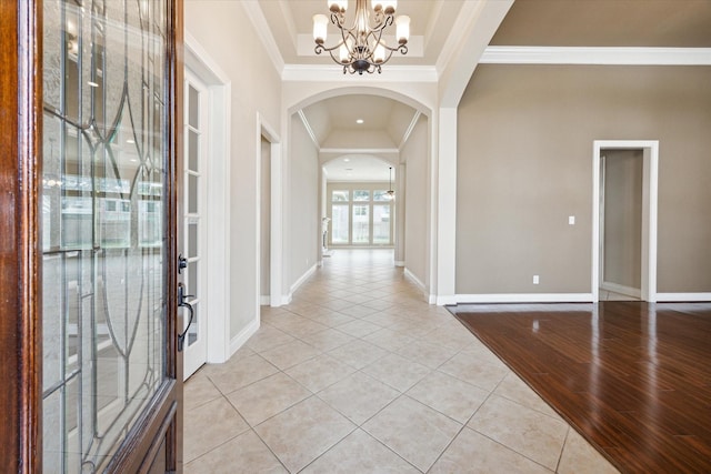 foyer featuring light hardwood / wood-style floors, crown molding, and an inviting chandelier