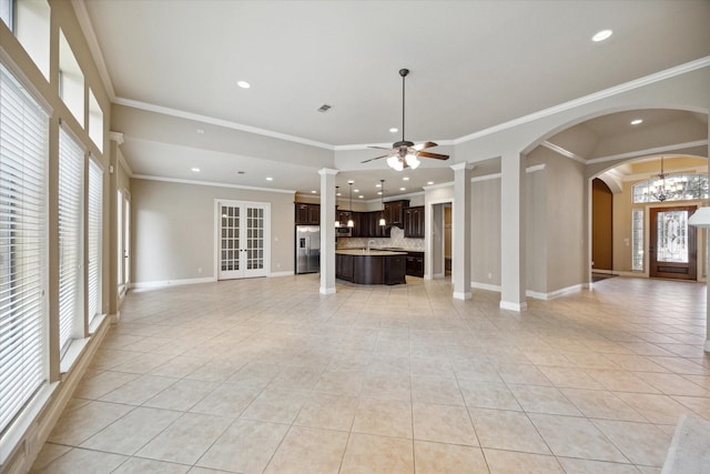 unfurnished living room featuring light tile patterned floors, ceiling fan with notable chandelier, and ornamental molding