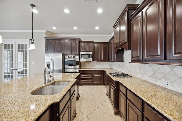 kitchen featuring light stone counters, dark brown cabinetry, stainless steel appliances, sink, and pendant lighting