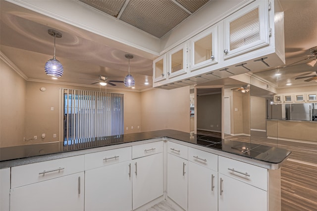 kitchen featuring kitchen peninsula, decorative light fixtures, stainless steel refrigerator, and white cabinets