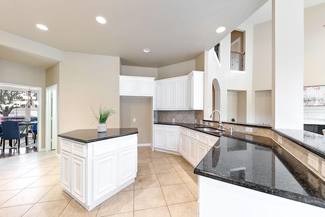 kitchen featuring dark stone counters, white cabinets, sink, tasteful backsplash, and kitchen peninsula