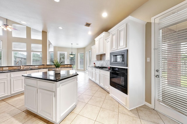 kitchen with backsplash, a kitchen island, built in microwave, black oven, and hanging light fixtures