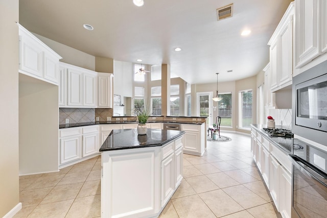 kitchen with white cabinets, appliances with stainless steel finishes, a center island, and light tile patterned floors