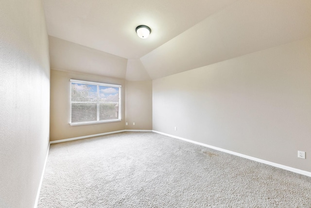 spare room featuring carpet flooring and vaulted ceiling