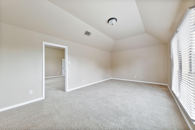 unfurnished room featuring lofted ceiling and light carpet