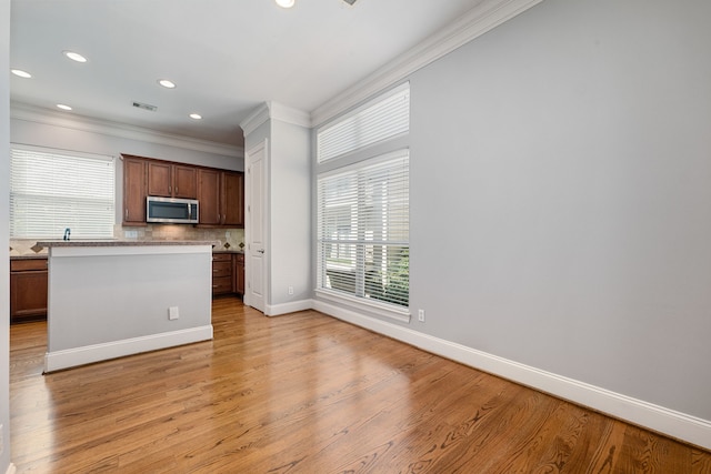 kitchen featuring light hardwood / wood-style floors, crown molding, and backsplash