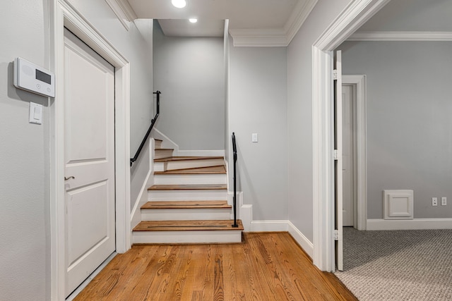 staircase with crown molding and wood-type flooring