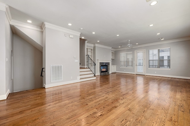 unfurnished living room featuring ceiling fan, light hardwood / wood-style floors, a premium fireplace, and crown molding