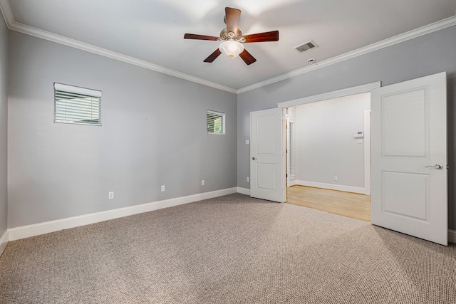 carpeted empty room with ceiling fan, plenty of natural light, and crown molding