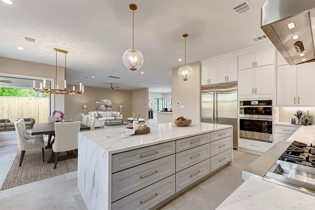 kitchen with light stone countertops, appliances with stainless steel finishes, a wealth of natural light, and pendant lighting