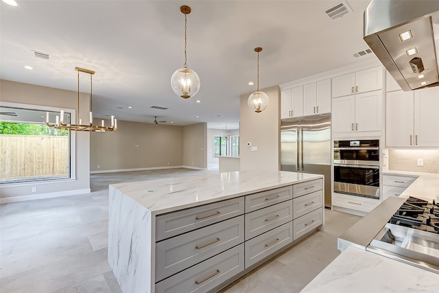 kitchen featuring stainless steel appliances, a center island, decorative light fixtures, white cabinetry, and light stone counters