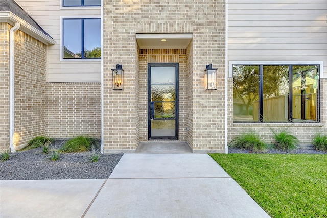 view of exterior entry featuring a lawn