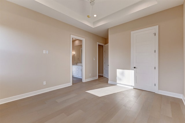 spare room with a tray ceiling and light hardwood / wood-style floors