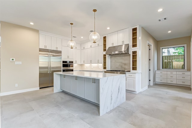 kitchen featuring tasteful backsplash, appliances with stainless steel finishes, a center island, hanging light fixtures, and white cabinetry