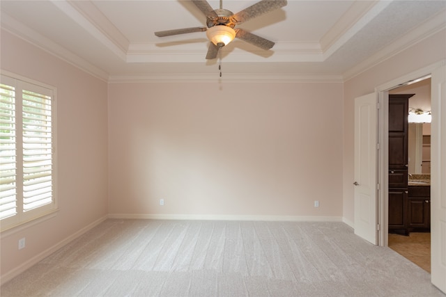 unfurnished room with crown molding, a tray ceiling, and light colored carpet