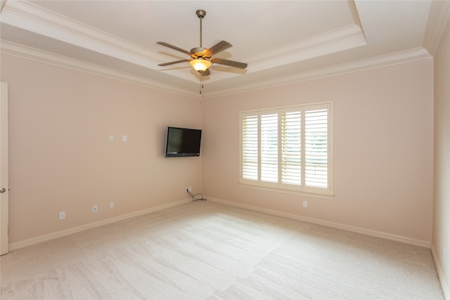 empty room featuring ceiling fan, crown molding, a tray ceiling, and light carpet