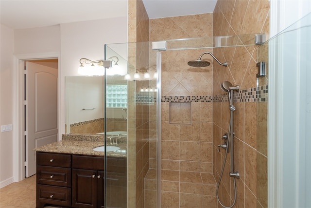 bathroom with vanity, a tile shower, and tile patterned flooring