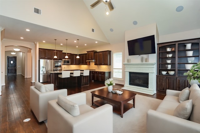 living room featuring dark wood-type flooring, ceiling fan, and high vaulted ceiling