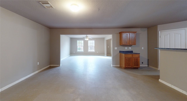 unfurnished living room featuring a textured ceiling and ceiling fan