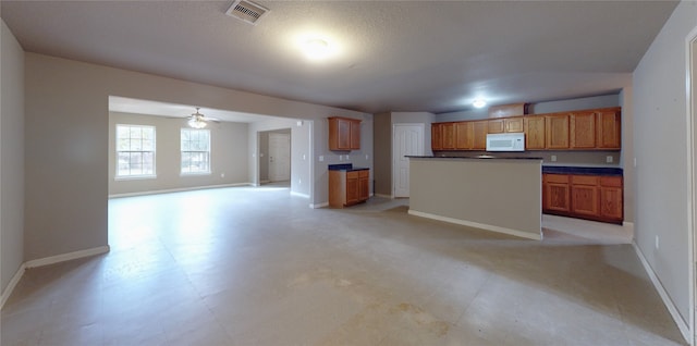 kitchen with a textured ceiling, a kitchen island, and ceiling fan