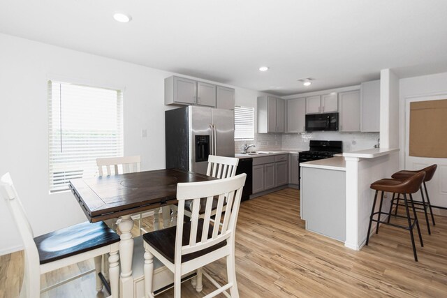 122 Austin Rd, Angleton, TX 77515 - kitchen with a healthy amount of sunlight, a kitchen bar, black appliances, and gray cabinets