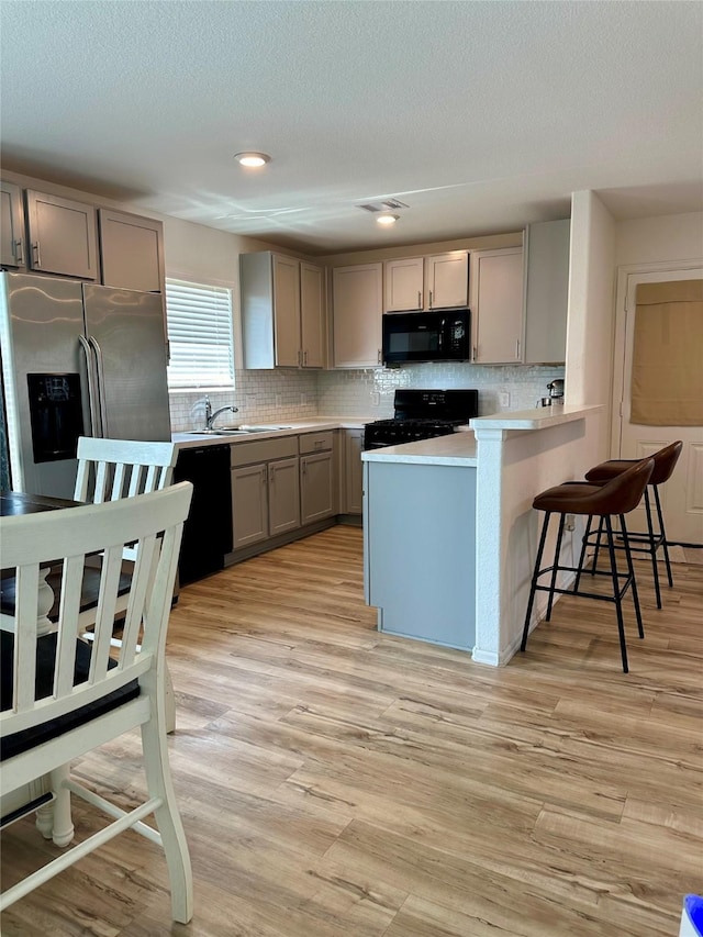 122 Austin Rd, Angleton, TX 77515 - kitchen featuring a peninsula, gray cabinetry, decorative backsplash, and black appliances