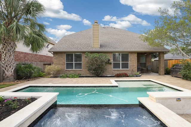 view of swimming pool with a grill, pool water feature, an in ground hot tub, and a patio area