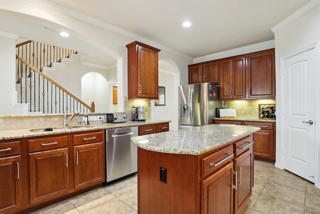 kitchen with stainless steel appliances, a center island, sink, ornamental molding, and light stone countertops