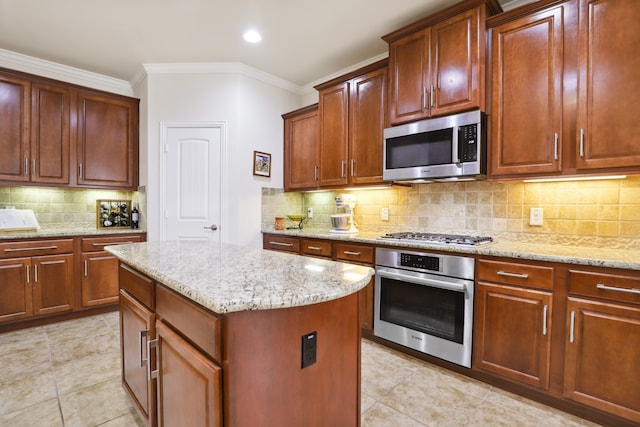 kitchen with stainless steel appliances, decorative backsplash, crown molding, a kitchen island, and light stone countertops