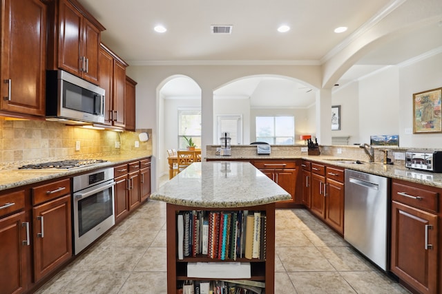 kitchen with light stone countertops, sink, a center island, and stainless steel appliances