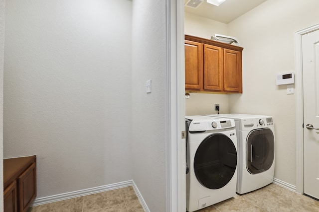 washroom with cabinets, washing machine and dryer, and light tile patterned floors