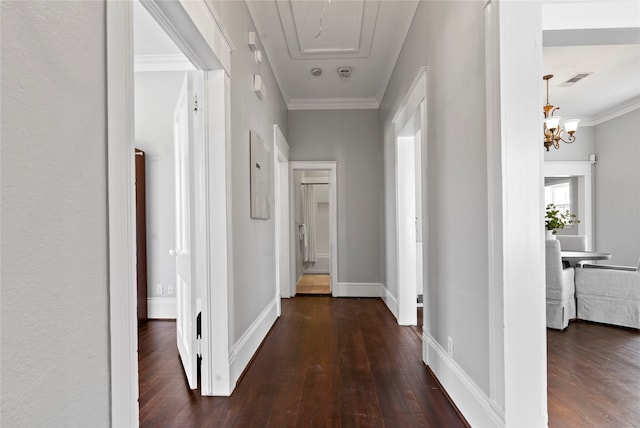 hallway with ornamental molding, dark wood-type flooring, and a notable chandelier