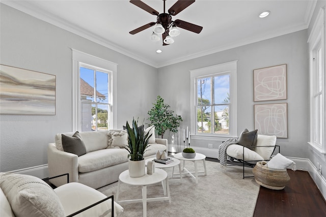 living room with a wealth of natural light, crown molding, wood-type flooring, and ceiling fan