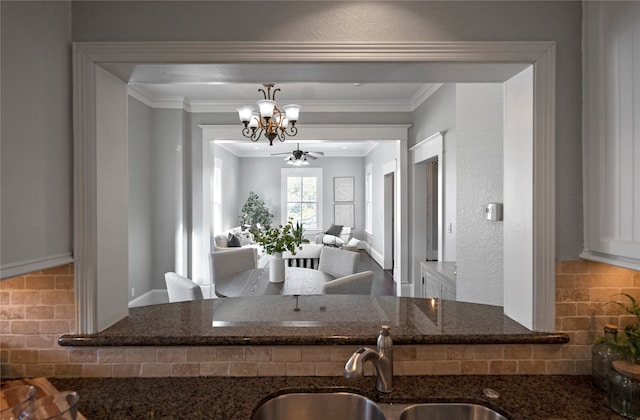 kitchen with backsplash, dark stone countertops, ornamental molding, sink, and ceiling fan